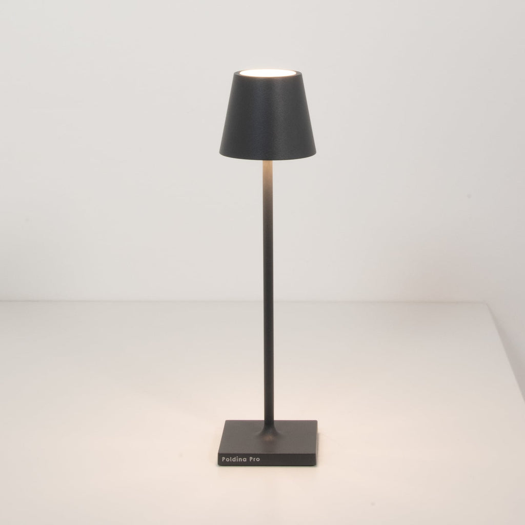 Nærbilde av LED oppladbar bordlampe Poldina micro mørkegrå IP65 på bord
