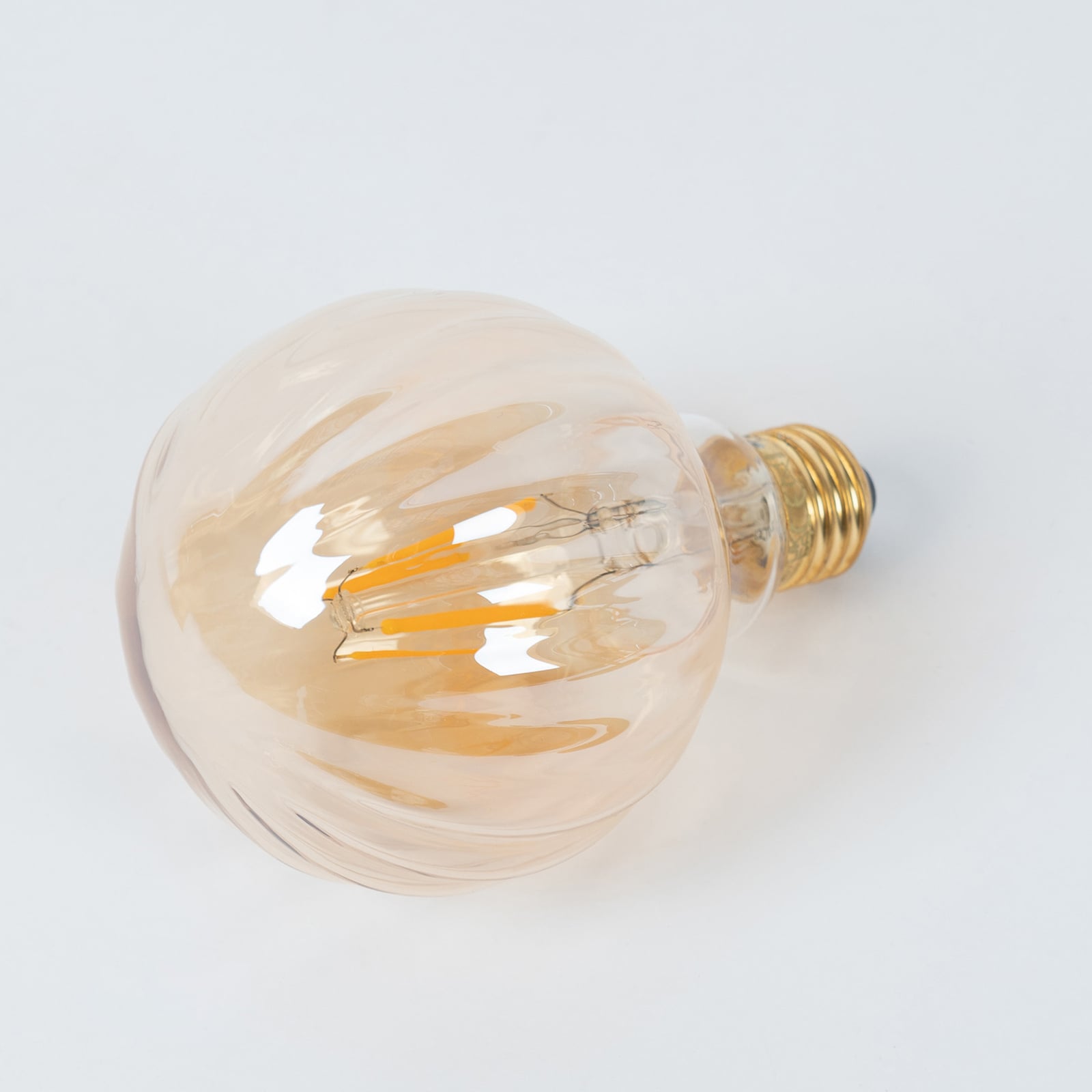 Nærbilde av amberfarget LED filamentpære E27 G95 3,8W 2700K dimbar